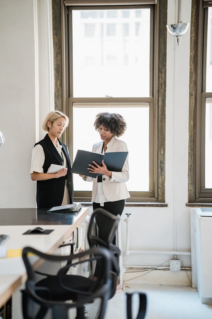 Mastering the First Impression: Your intriguing post title goes here Two women discussing work in a bright, modern office setting.